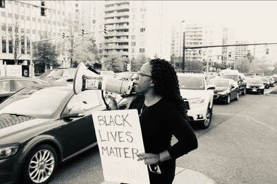 A woman is holding a sign and a megaphone.